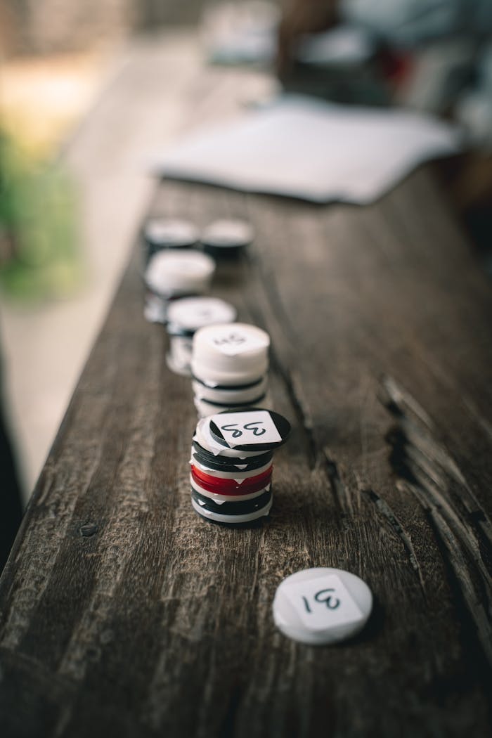 Close-up view of numbered poker chips stacked on a wooden surface for gaming or gambling.