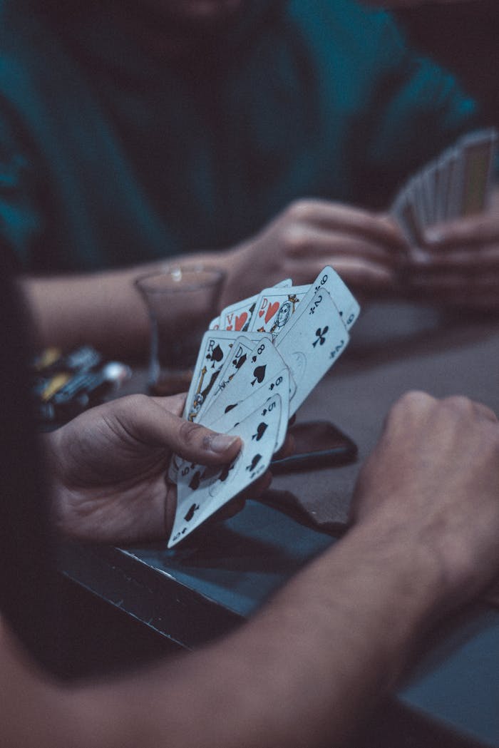 A close-up shot of hands holding playing cards during a game, creating a tense atmosphere.