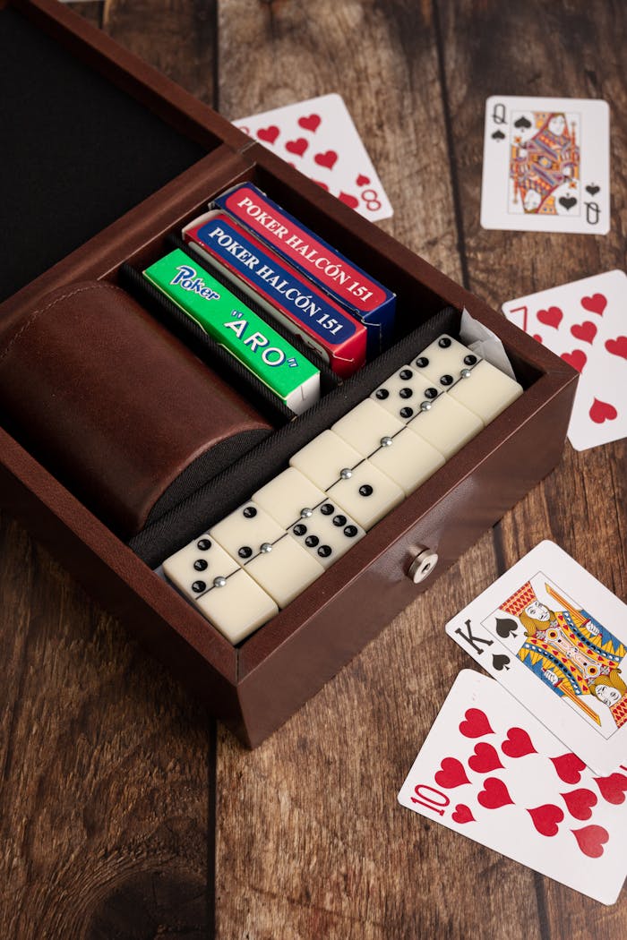 Wooden game box containing playing cards and dominoes on wooden table.