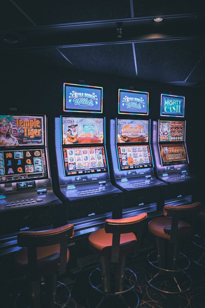 about-02 Row of illuminated slot machines in a dimly lit, empty casino area.