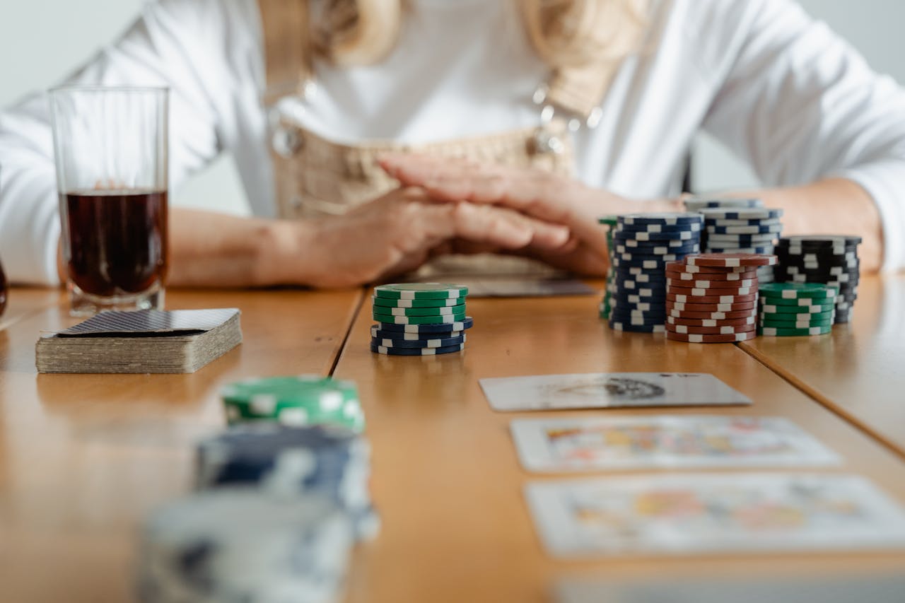 Senior woman playing poker with cards and chips on a wooden table indoors.