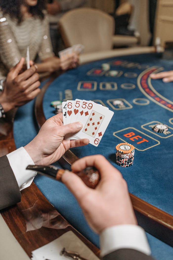 A close-up of players engaged in a poker game at a casino table, showcasing cards and chips.
