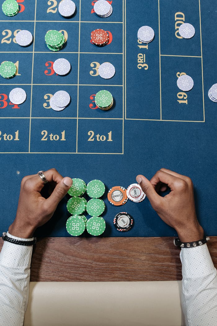 Hands arranging chips on a roulette table in a casino setting.